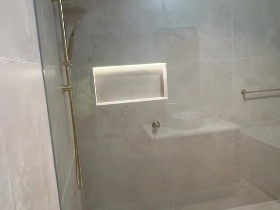 Shower with linear drain and gold tapware