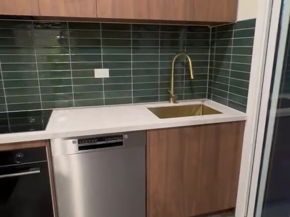 Granny flat kitchenette with green subway tile splashback, timber cabinetry and brushed gold tapware